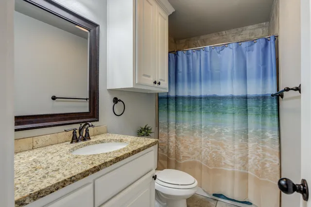a bathroom with a granite countertop sink a toilet and shower