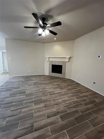 a view of an empty room with wooden floor and a ceiling fan