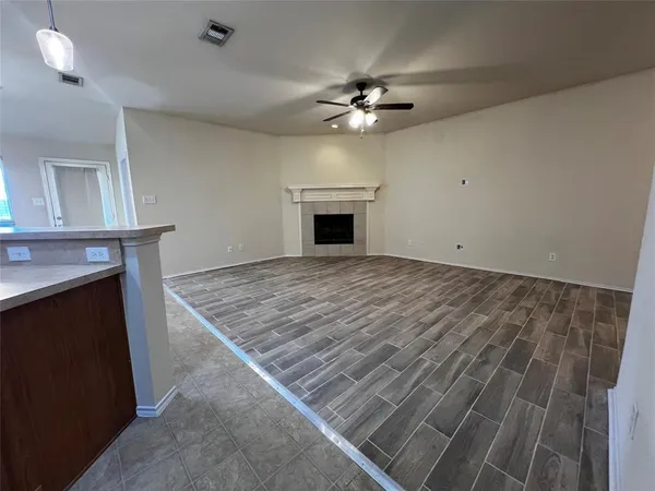 a view of an empty room with chandelier fan and fire place