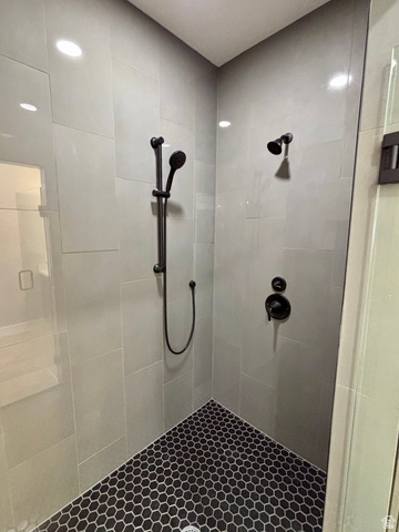 1184 West 3250 North Ogden, UT 84414 - Photo 32 of 69 Modern shower enclosure featuring gray rectangular wall tiles, dark hexagonal floor tiles, a handheld shower fixture, a fixed shower head, and matte black hardware