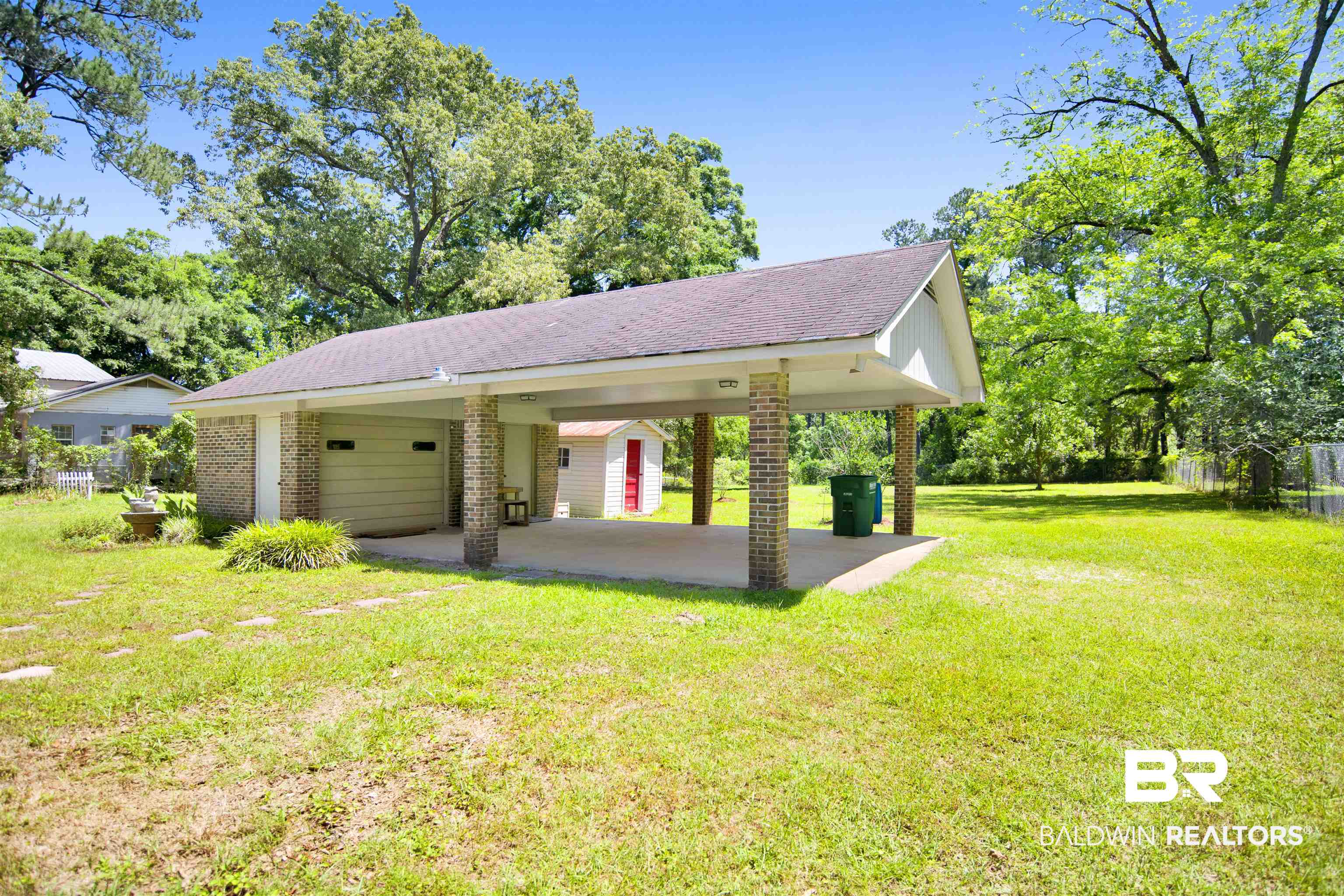 30888 Cemetery Road Daphne, AL 36527 - Photo 26 of 36 Detached carport and garage structure featuring brick columns, a covered concrete pad, and a roll-up garage door
