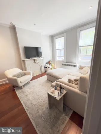 a view of a hallway with wooden floor and a bathroom