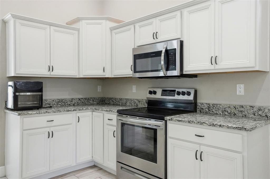 4128 Everett Avenue Spring Hill, FL 34609 - Photo 11 of 57 a kitchen with white cabinets granite counter and stainless steel appliances