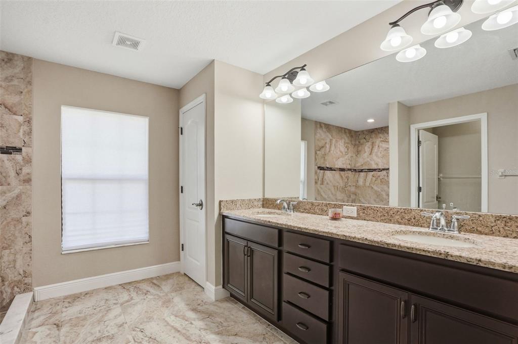 4128 Everett Avenue Spring Hill, FL 34609 - Photo 30 of 57 a bathroom with a granite countertop sink a large mirror and a window