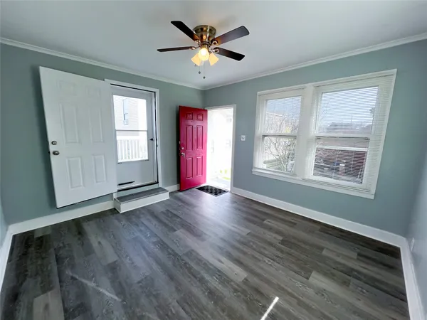 a view of an empty room with wooden floor and a window