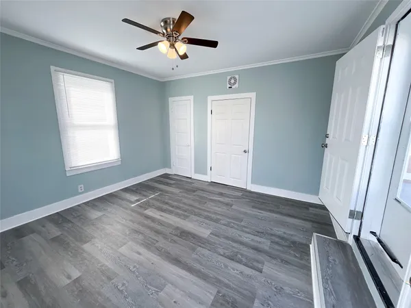 a view of empty room with wooden floor and fan