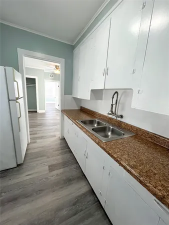 a kitchen with a sink a refrigerator and wooden floor