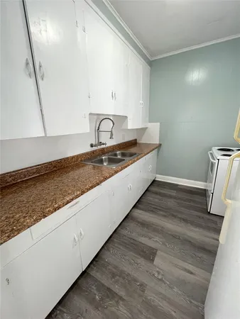 a large kitchen with a sink and washing machine with wooden floor