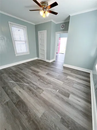 an empty room with wooden floor fan and windows