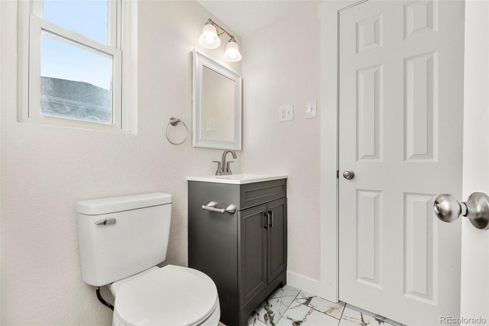 1216 Ursula Street Aurora, CO 80011 - Photo 20 of 30 a bathroom with a toilet a sink and mirror