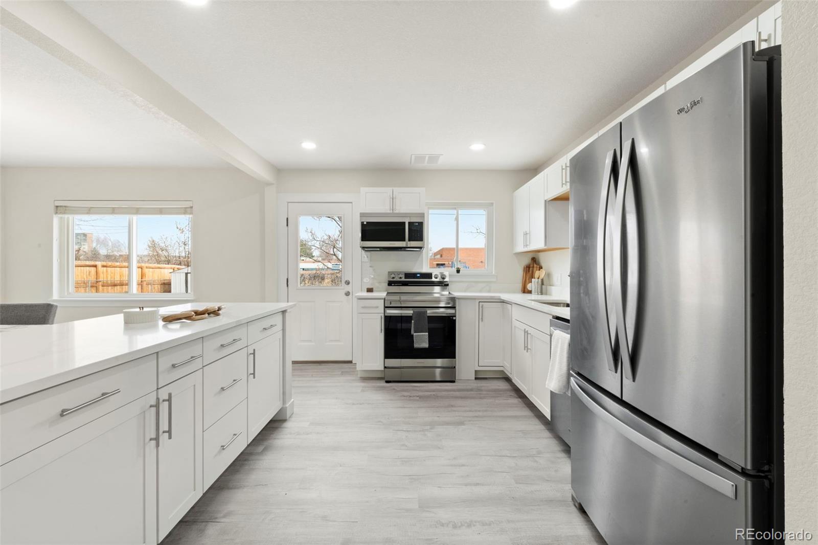 1216 Ursula Street Aurora, CO 80011 - Photo 3 of 30 a kitchen with white cabinets and stainless steel appliances