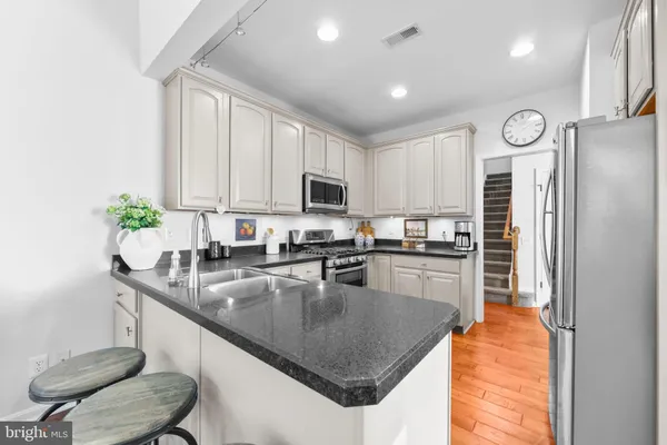 a kitchen with granite countertop a sink a counter top space appliances and cabinets