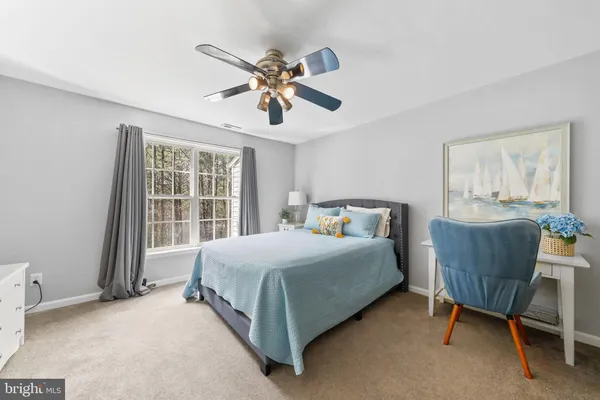 a bedroom with a bed a chair and a large window