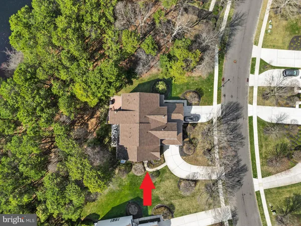 an aerial view of a house with large trees and playing ground