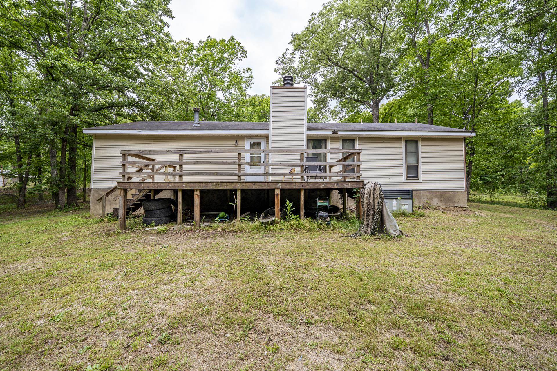 259 Oakview Drive Adamsville, TN 38310 - Photo 27 of 32 Rear exterior featuring a raised wood deck with railing, a light-colored siding facade, and a prominent chimney