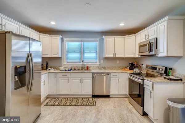 a kitchen with stainless steel appliances granite countertop a stove a sink and a refrigerator