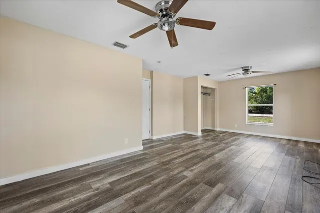 a view of hallway with wooden floor and fan