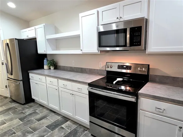 a kitchen with stainless steel appliances granite countertop a stove microwave and refrigerator