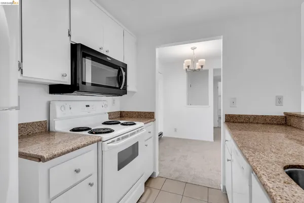 a kitchen with granite countertop a stove sink and microwave