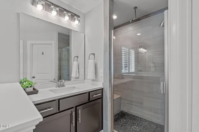 a bathroom with a sink shower and a mirror