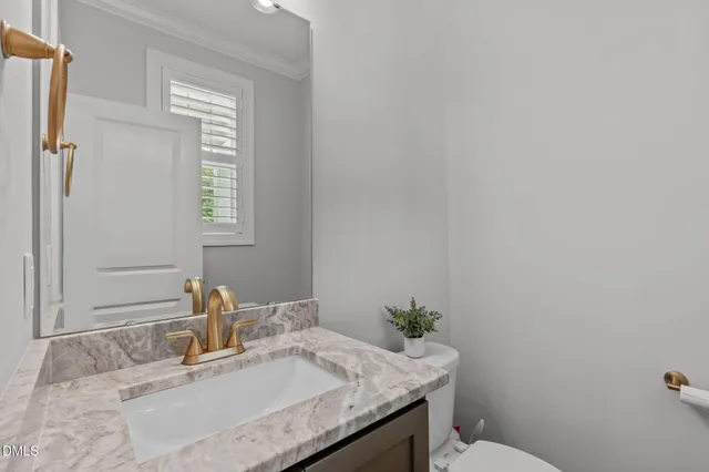 a bathroom with a granite countertop sink a mirror and a toilet