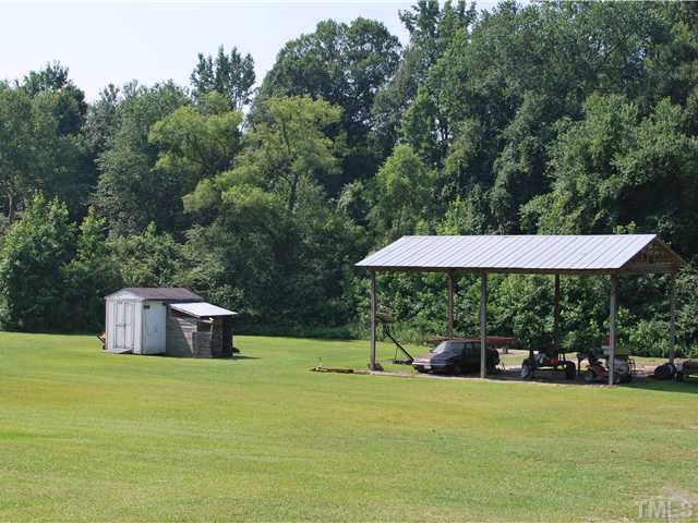 2445 Zacks Mill Road Angier, NC 27501 - Photo 9 of 15 a backyard of a house with table and chairs under an umbrella