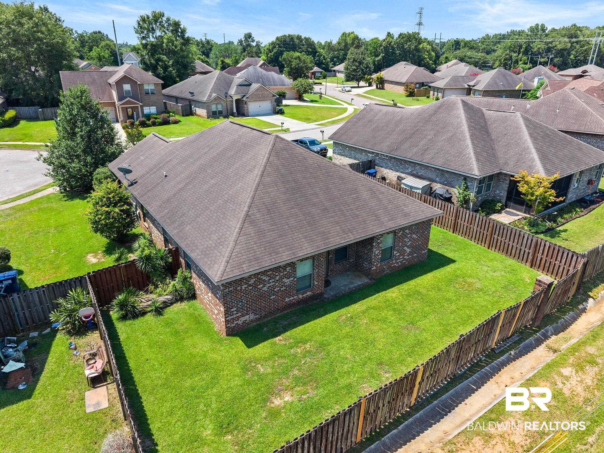 2216 Livingstone Court Mobile, AL 36695 - Photo 49 of 62 Brick exterior residence with a shingled roof, featuring a fenced backyard with manicured lawn and perimeter landscaping