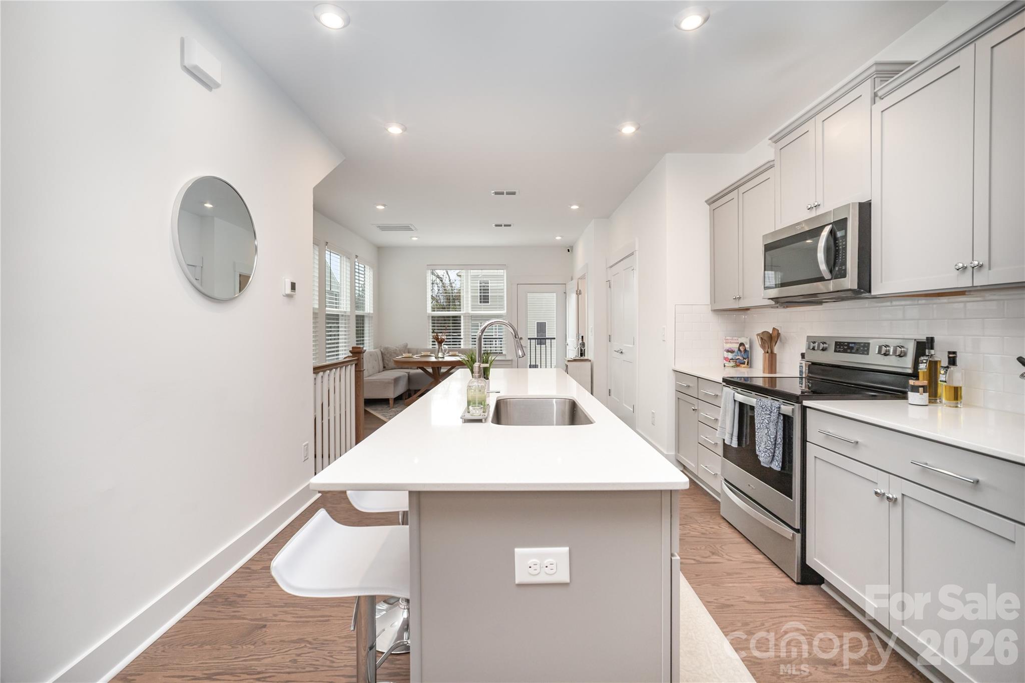 4004 Capital Ridge Charlotte, NC 28205 - Photo 10 of 30 a kitchen with stainless steel appliances kitchen island granite countertop a sink a stove a dining table and chairs with wooden floor