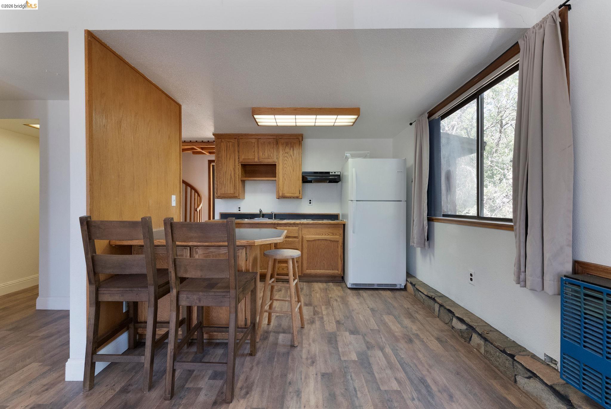 22963 Robertson Ranch Road Sonora, CA 95370 - Photo 59 of 90 Compact kitchen area featuring wood-finish flooring, wood cabinetry, dark countertops, and a white refrigerator