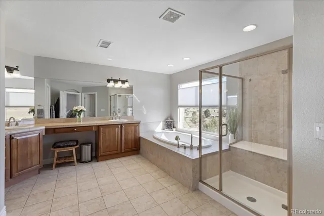 a spacious en suite bathroom with a mirror a double vanity sink and bathtub