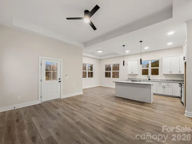 a large white kitchen with kitchen island a sink stainless steel appliances and cabinets