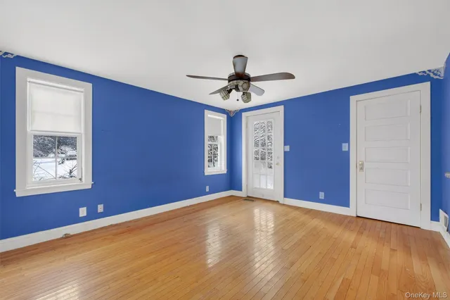 a view of an empty room with chandelier fan and wooden floor