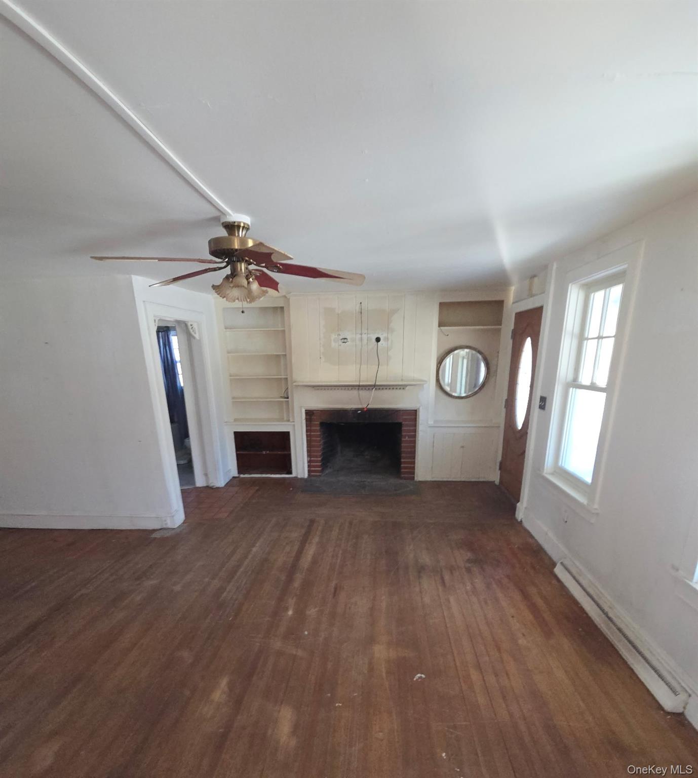 91 Clove Branch Road Hopewell Junction, NY 12533 - Photo 5 of 8 an empty room with windows fireplace and wooden floor