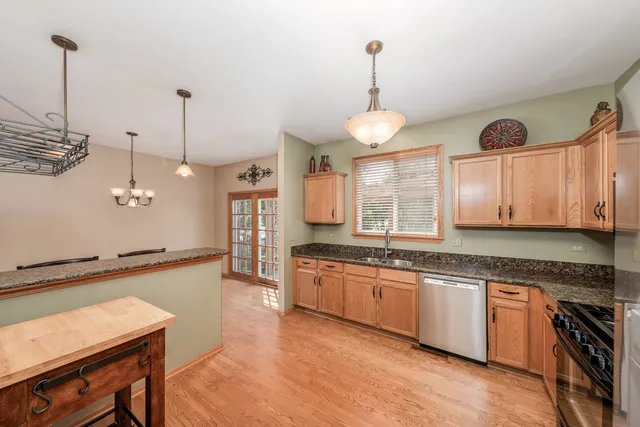 a large kitchen with stainless steel appliances granite countertop a stove a sink dishwasher a dining table and chairs with wooden floor