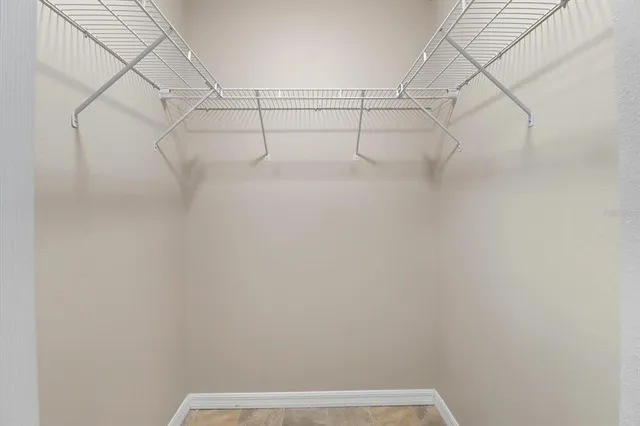 an empty room with chandelier fan and windows