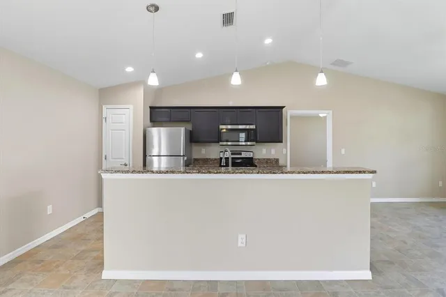 a kitchen with stainless steel appliances granite countertop a sink and a refrigerator