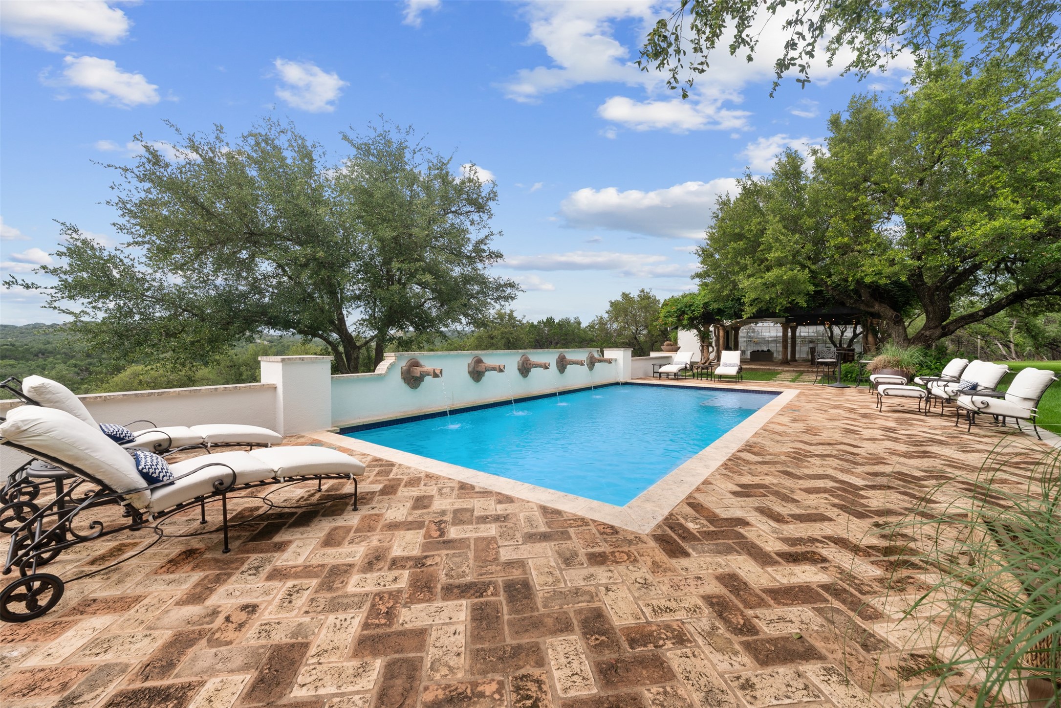 34000 Smithson Valley Road Bulverde, TX 78163 - Photo 33 of 50 Enjoy sweeping Hill Country views from the resort-inspired pool featuring dramatic water-wall fountains and expansive brick decking. Mature oak trees provide beauty, privacy, and natural shade throughout the outdoor living areas.
