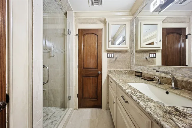 a bathroom with a granite countertop double vanity sink a mirror and a shower