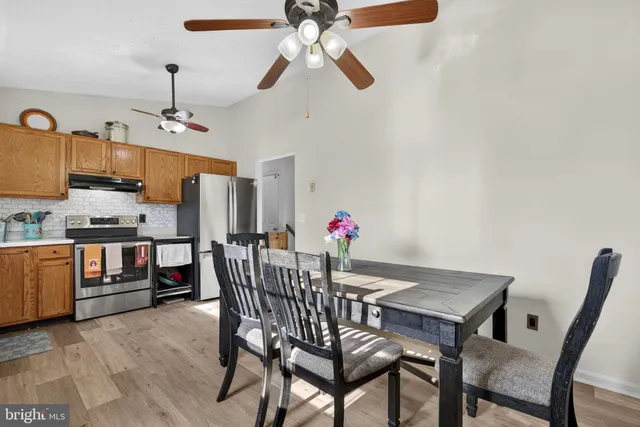 a kitchen with stainless steel appliances granite countertop a refrigerator a sink dishwasher a dining table and chairs with wooden floor