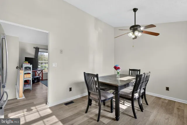 a kitchen with granite countertop a refrigerator a sink dishwasher a stove top oven a dining table and chairs with wooden floor