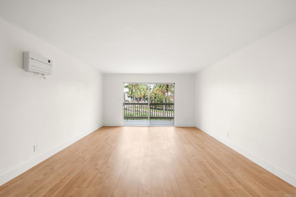 4444 West Point Loma Boulevard, Unit 122 San Diego, CA 92107 - Photo 7 of 25 an empty room with wooden floor and windows
