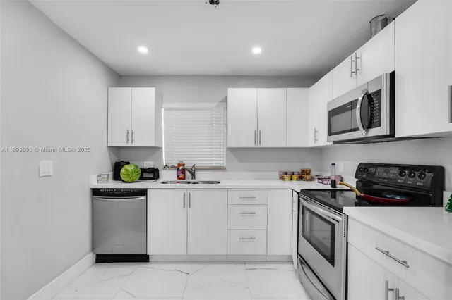a kitchen with stainless steel appliances granite countertop white cabinets sink and stove top oven
