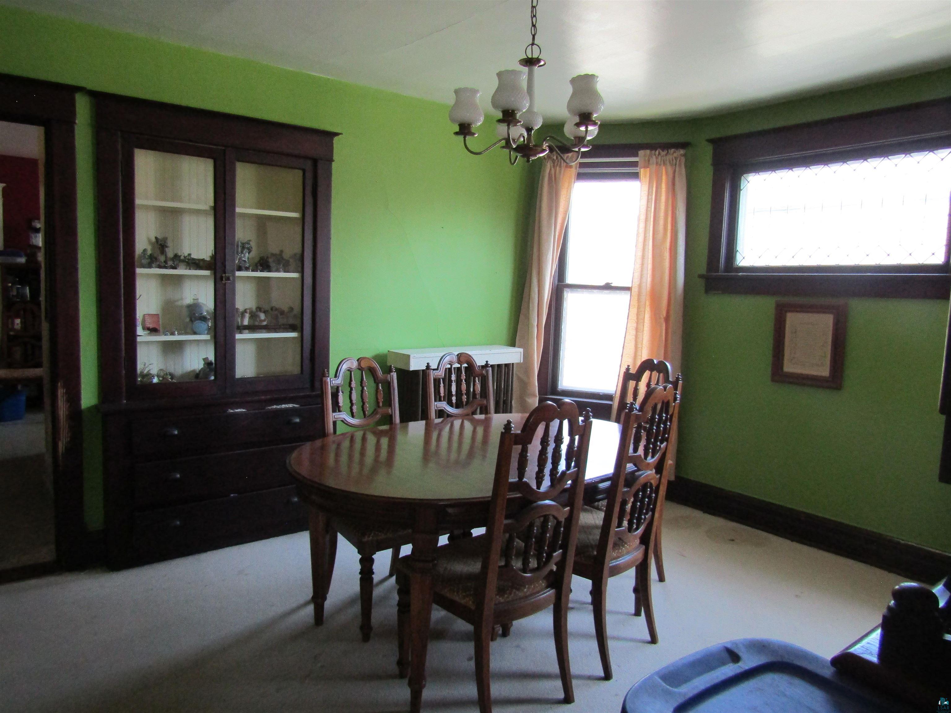 1115 Harrison Street Superior, WI 54880 - Photo 34 of 49 Dining area featuring a built-in display cabinet with glass doors, a multi-light chandelier, a bay window, and dark wood trim