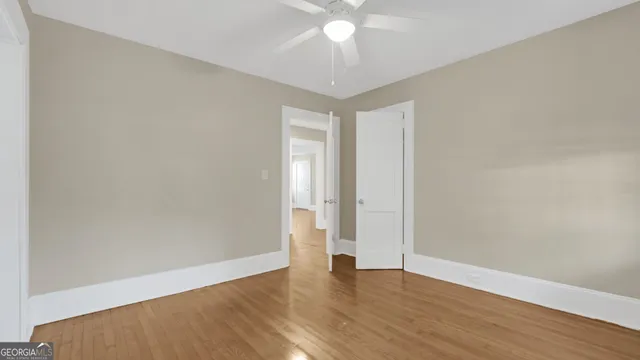 a view of an empty room with wooden floor and windows
