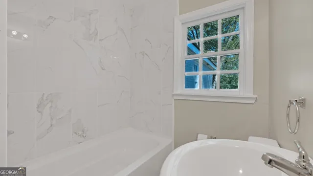 a bath tub sitting next to a white sink and a toilet
