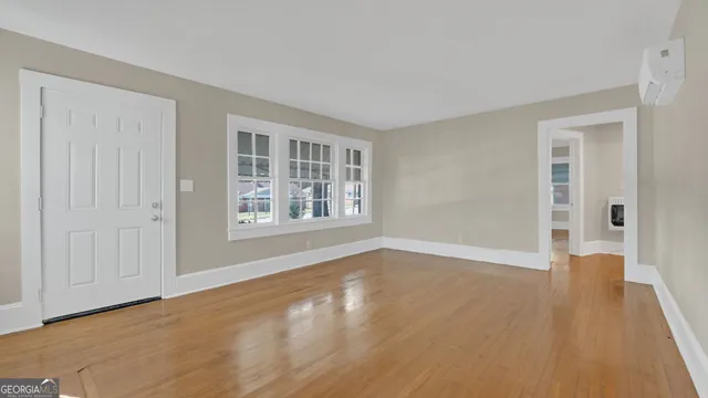 a view of an empty room with window and wooden floor