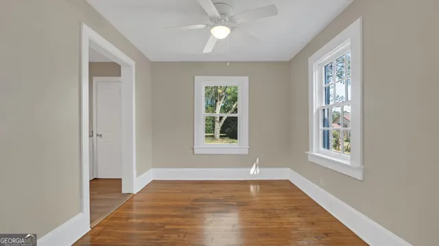 a view of an empty room with wooden floor and a window