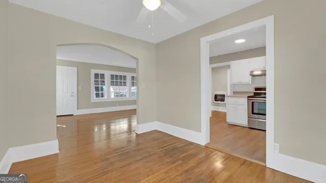 a view of a hallway with wooden floor and a kitchen