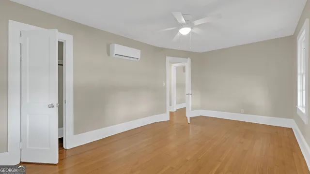 an empty room with wooden floor and a ceiling fan