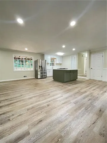 a view of kitchen and empty room with wooden floor